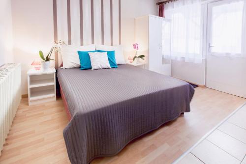 a bedroom with a large bed with blue and white pillows at Apartman Szanyi in Bük