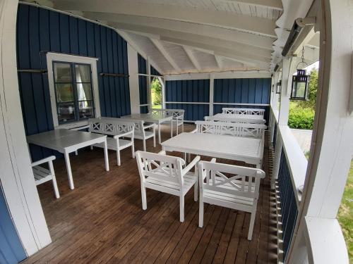 Sysslebäck的住宿－Wärdshuset Klarälvdalen，带顶棚的门廊配有白色的桌子和白色的椅子