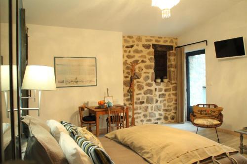a living room with a bed and a stone wall at La Demeure des Maitres in Chirols