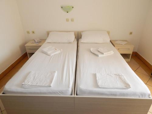 two beds with white sheets in a room at Guest House Frane in Pag
