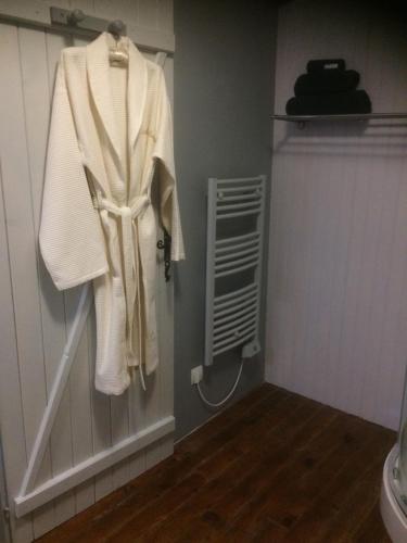 La salle de bains est pourvue d'un peignoir blanc accroché au mur. dans l'établissement Michouat Chambre D'Hotes, à Vidou