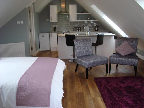 a bedroom with a bed and two chairs and a kitchen at Spring Paddocks B&B in Furneux Pelham