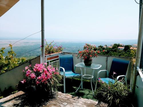 een balkon met een tafel, stoelen en bloemen bij Abramichi Guest House in Sighnaghi