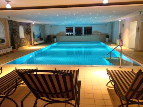 ein großer Pool mit zwei Stühlen davor in der Unterkunft Hotel Braunschweiger Hof in Bad Harzburg