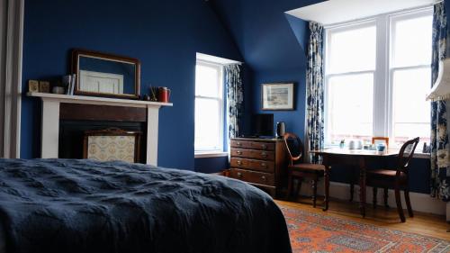een slaapkamer met blauwe muren en een tafel en een bed bij Denson Villa in Nairn