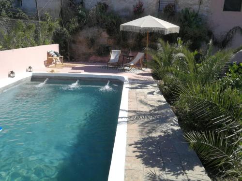 una piscina en un patio con sombrilla en La Casa Grande de Zujaira, en Zujaira