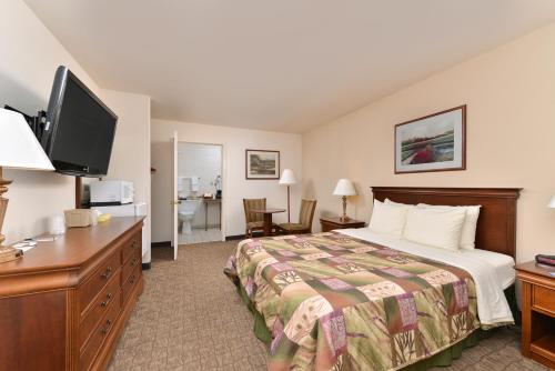 um quarto de hotel com uma cama e uma televisão de ecrã plano em The Heritage Inn, Inc em Huntingdon