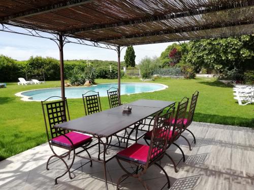 una mesa y sillas bajo una pérgola junto a una piscina en A la Maison d'Hôtes, en La Baume-de-Transit