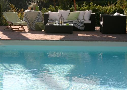 a pool with a couch and chairs next to a table at La Pintura in Trevi