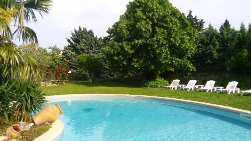 a large swimming pool with white chairs and trees at A la Maison d'Hôtes in La Baume-de-Transit