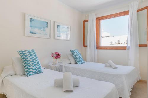 Habitación blanca con 2 camas y ventana en YupiHome Can Jaume Apartment, en Alcudia