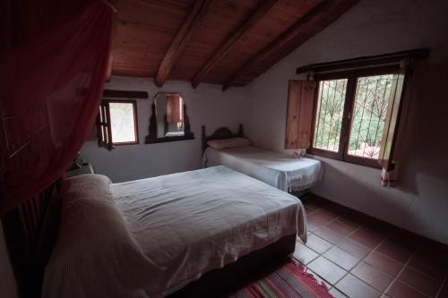 1 dormitorio con 2 camas y 2 ventanas en La Toscana en Linares de la Sierra