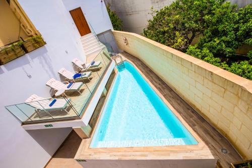 una piscina con 2 tumbonas y una piscina en Pjazza Suites Boutique Hotel by CX Collection, en Siġġiewi