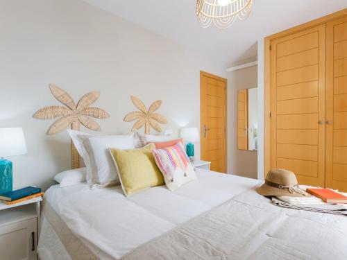a bedroom with a large white bed with colorful pillows at La Marina II, luminoso apartamento junto a la playa in Torre de Benagalbón