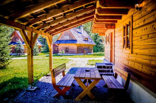a wooden picnic table on the porch of a cabin at Hotel****Liptovský dvor in Liptovský Ján