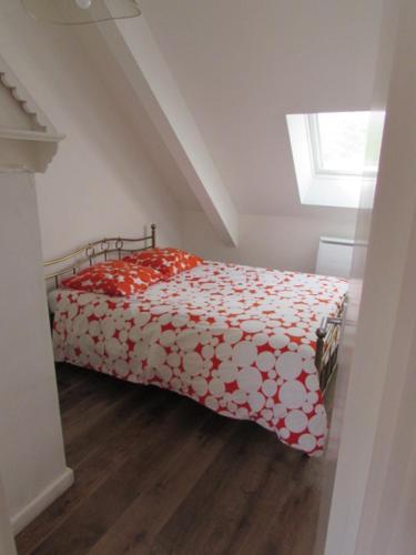 a bedroom with a bed with a red and white comforter at Fisherman's cottage in Ile d'Arz