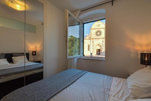 a bedroom with a bed and a window with a clock tower at Apartment Oliveto Sibenik in Šibenik
