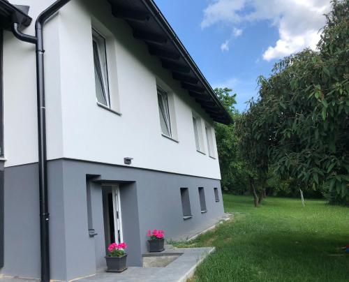 a white building with pink flowers in a yard at Pozlovice - Apartmán Sisi in Luhačovice