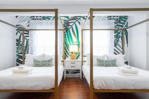 two beds in a room with two windows at The Cherry Suites - Chinatown in Philadelphia