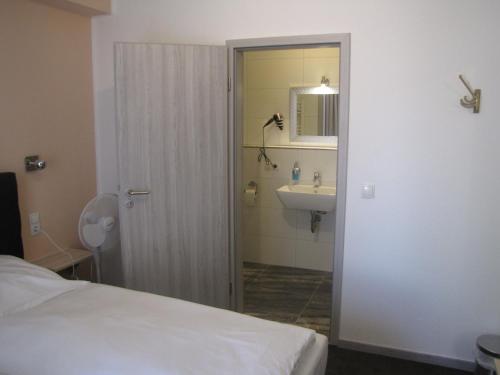y baño con cama, lavabo y espejo. en Milano Hotel, en Hamburgo