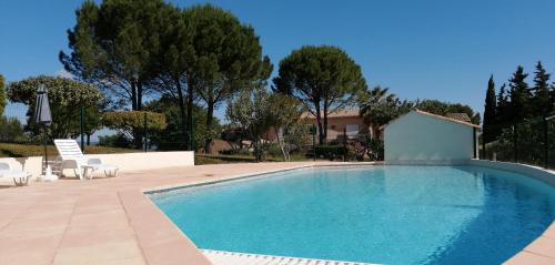 une piscine avec des chaises et une maison dans l'établissement LES 3 HIRONDELLES, à Pont-Saint-Esprit