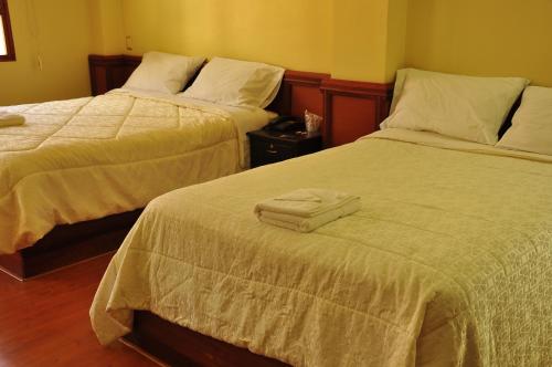 two beds in a hotel room with towels on them at Hotel Donde Marcelo in Baños