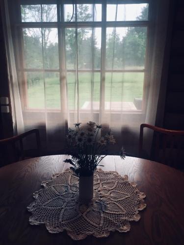 a vase with flowers on a table in front of a window at Purje Holiday Home in Heltermaa