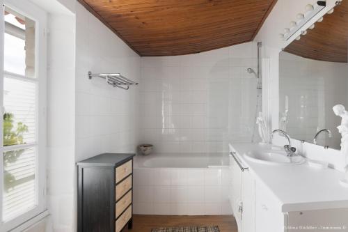 een witte badkamer met een bad en een wastafel bij Le Clos du Vieux Porche in La Couarde-sur-Mer