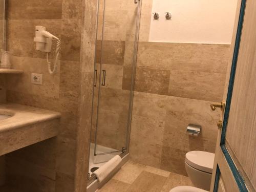 a bathroom with a toilet, sink, and shower stall at Hotel Riviera in Alghero