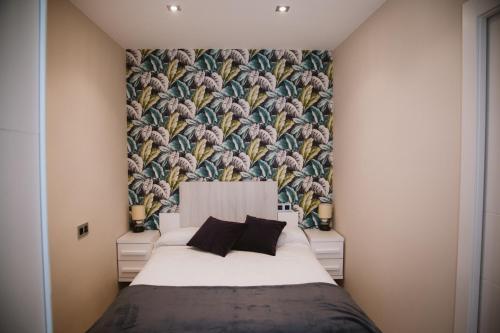 een slaapkamer met een groot bed met bloemenbehang bij La Atalaya, apartamento en Llanes in Llanes