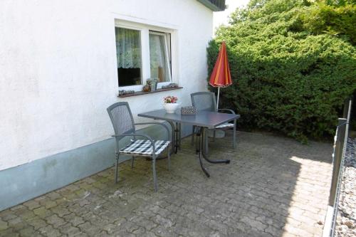 a patio with a table and chairs and a red umbrella at Ruegen_Fewo 67_1 in Thesenvitz