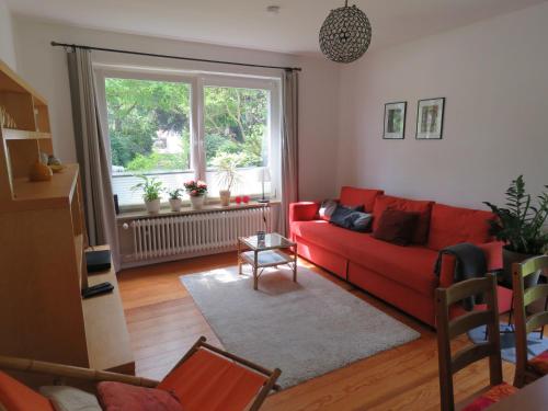 a living room with a red couch and a window at Marigold in Neumünster