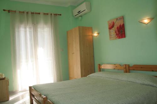 a bedroom with a bed in front of a window at Alexandros Rooms in Áno Stavrós