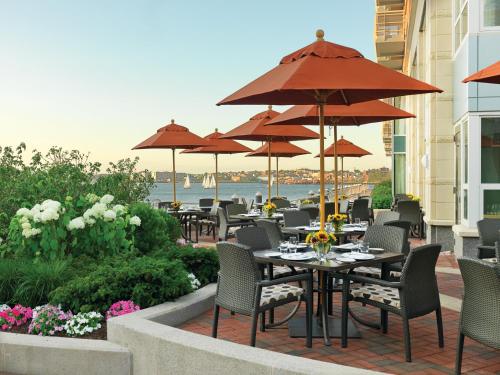 a patio with tables and chairs and umbrellas at Battery Wharf Hotel, Boston Waterfront in Boston
