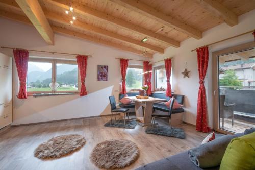 ein Wohnzimmer mit einem Tisch, Stühlen und Fenstern in der Unterkunft Alpinjuwel in Hippach in Hippach