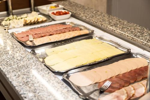 a buffet line with hot dogs and cheese at Stadthotel Alsfeld in Alsfeld