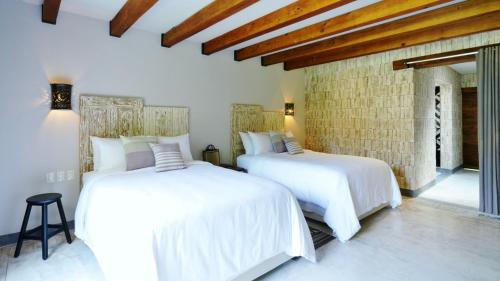 two beds in a bedroom with white sheets at Amomoxtli in Tepoztlán