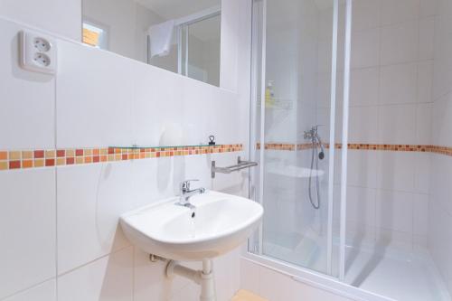 a white bathroom with a sink and a shower at Rodinný pension Bečov in Bečov nad Teplou