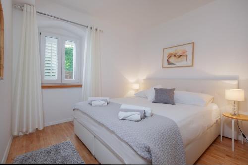 a white bedroom with a white bed and a window at Boutique Waterfront Apartments in Podgora