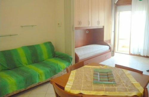 a living room with a green couch and a table at Appartamento Maestri in Sottomarina