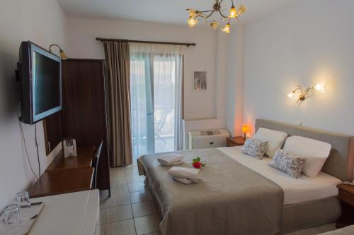 um quarto com uma cama grande e uma televisão. em HOTEL BARA em Neos Marmaras