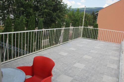 a red chair and a table on a balcony at Apartman KEJ in Pirot