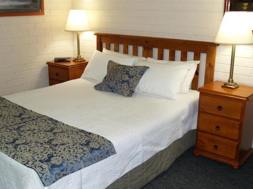 a hotel room with a bed and a lamp at Pigeon House Motor Inn in Ulladulla