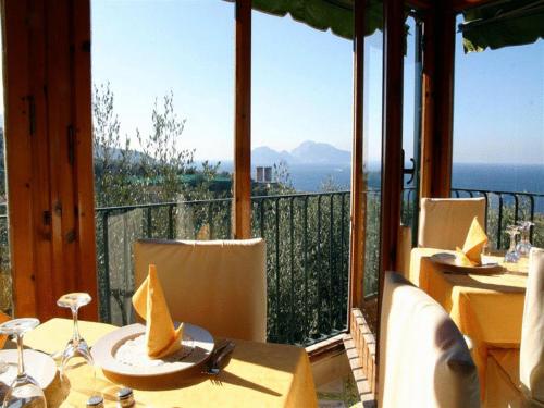 a restaurant with tables and chairs with a view of the ocean at Hotel Villa Pina Antico Francischiello in Massa Lubrense