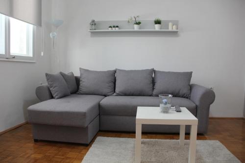 a living room with a gray couch and a white table at Apartman KEJ in Pirot
