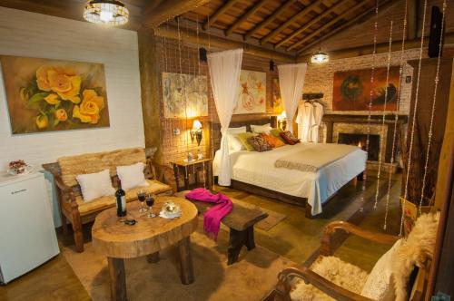 een slaapkamer met een bed, een bank en een tafel bij Pousada Alto da Neblina in Monte Verde
