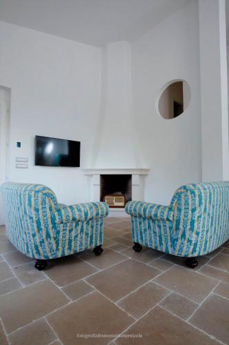two chairs in a living room with a fireplace at Residenza Lippolis in Castellana Grotte