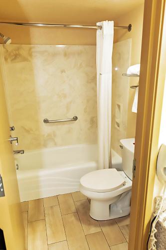 a bathroom with a toilet and a tub and a shower at Days Inn by Wyndham Oklahoma City in Oklahoma City