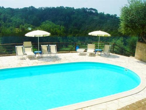 a large blue swimming pool with chairs and umbrellas at Fattoria Casanova in Palaia