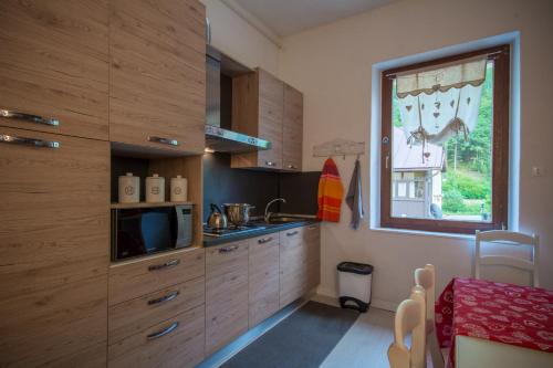 a kitchen with wooden cabinets and a window at La Casa di Davide - David Home in Cave del Predil
